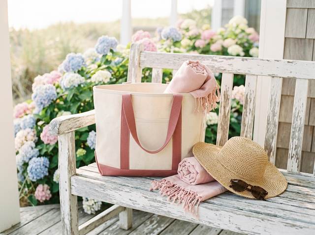 A canvas beach tote with pink trim and a straw hat.